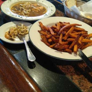 A plate of sweet potato fries and a bowl of soup.