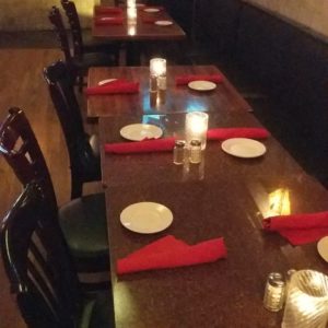 A restaurant with a long table and red napkins.