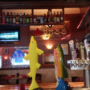 A bar with two fish statues on the bar.