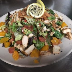 A plate of chicken salad with oranges and lemons on it.