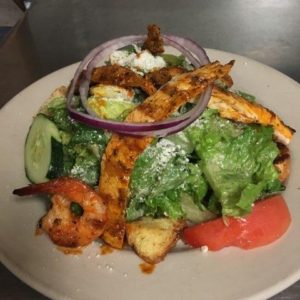 A plate with a salad and shrimp on it.