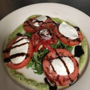 A plate with tomatoes and greens on it.