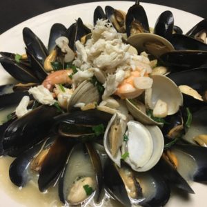 A plate of mussels and shrimp on a white plate.