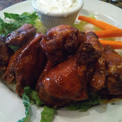 A plate with chicken wings and carrots on it.