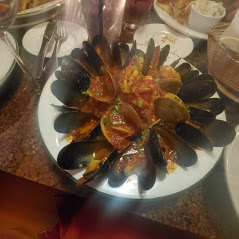 A plate of mussels with sauce on a table.
