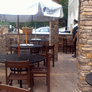 A brick patio with tables and chairs.