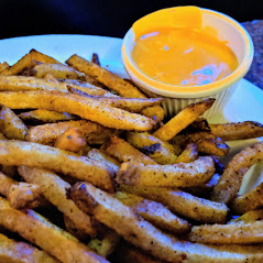 A plate of french fries with dipping sauce.