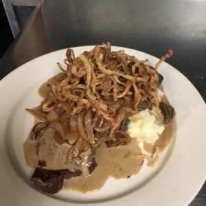 A plate with steak, mashed potatoes and gravy.