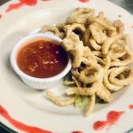 Onion rings on a plate with dipping sauce.