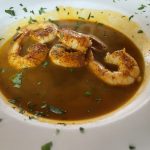 A bowl of soup with shrimp in it.