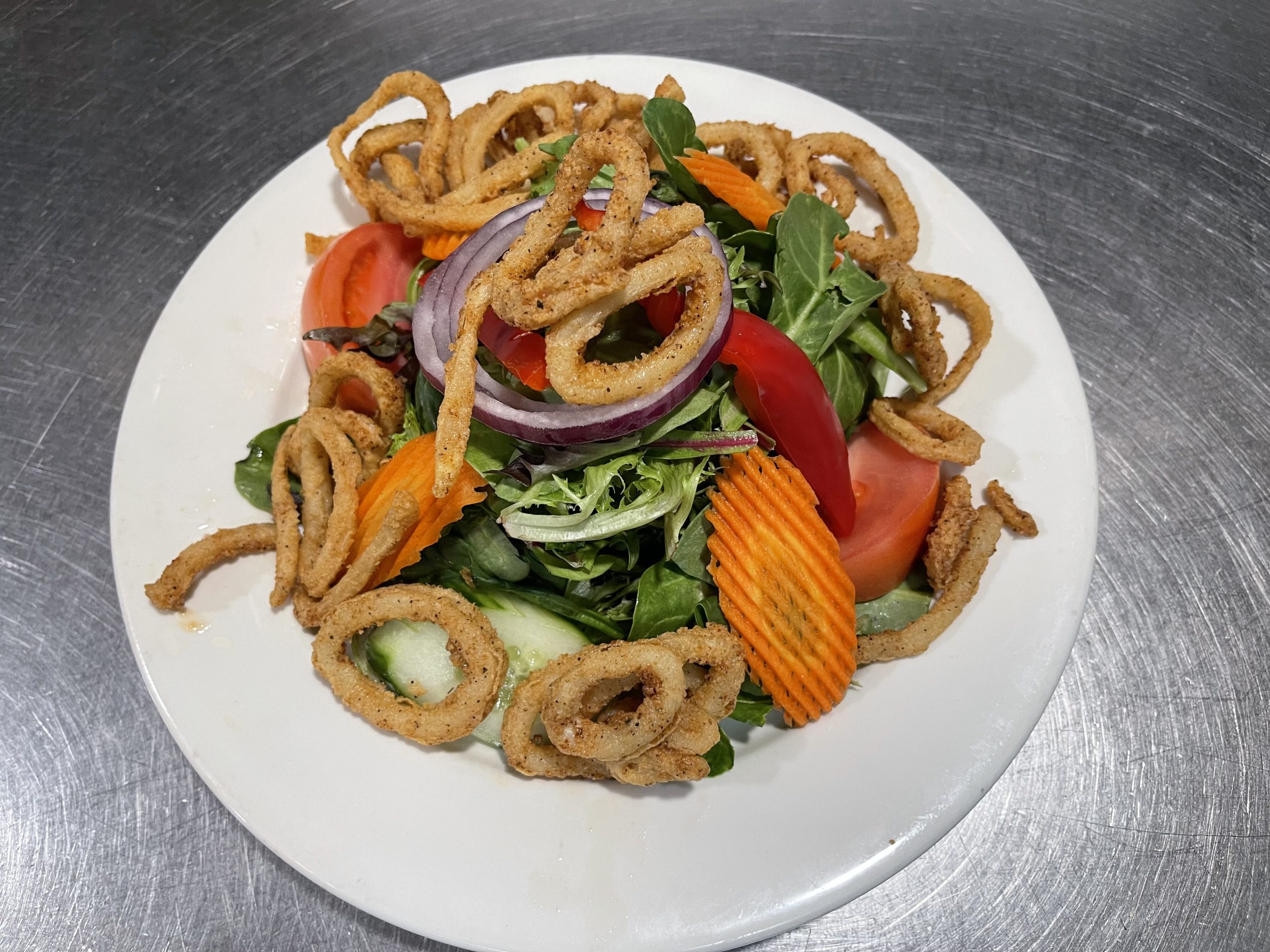 A salad with onion rings and vegetables on a plate.