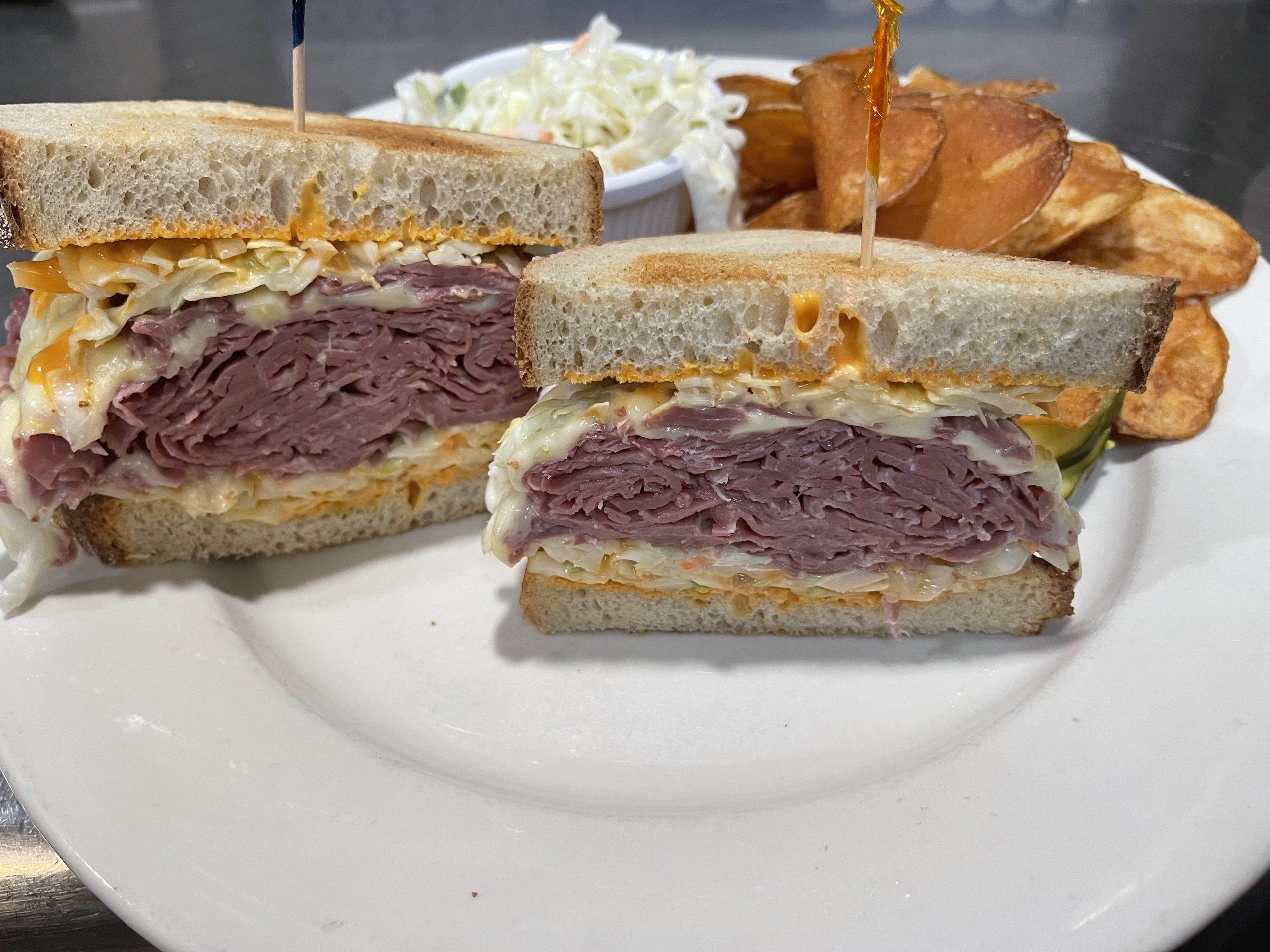 A sandwich with corned beef and coleslaw on a plate.