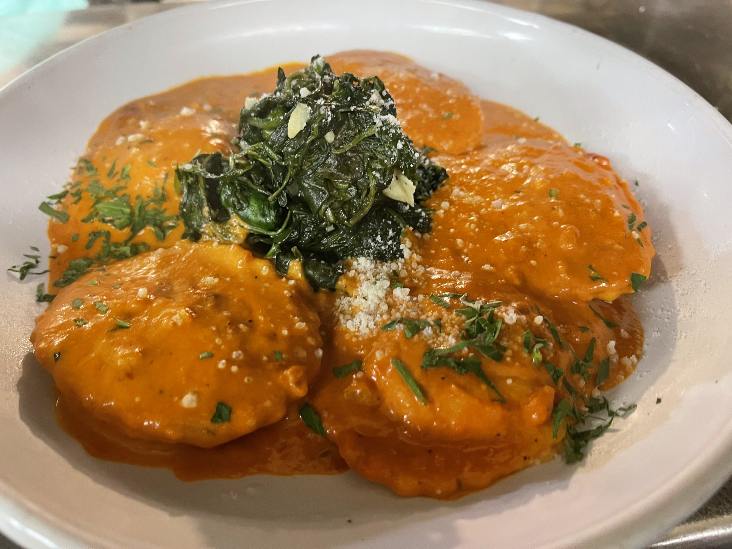 A plate of ravioli with spinach and parmesan.