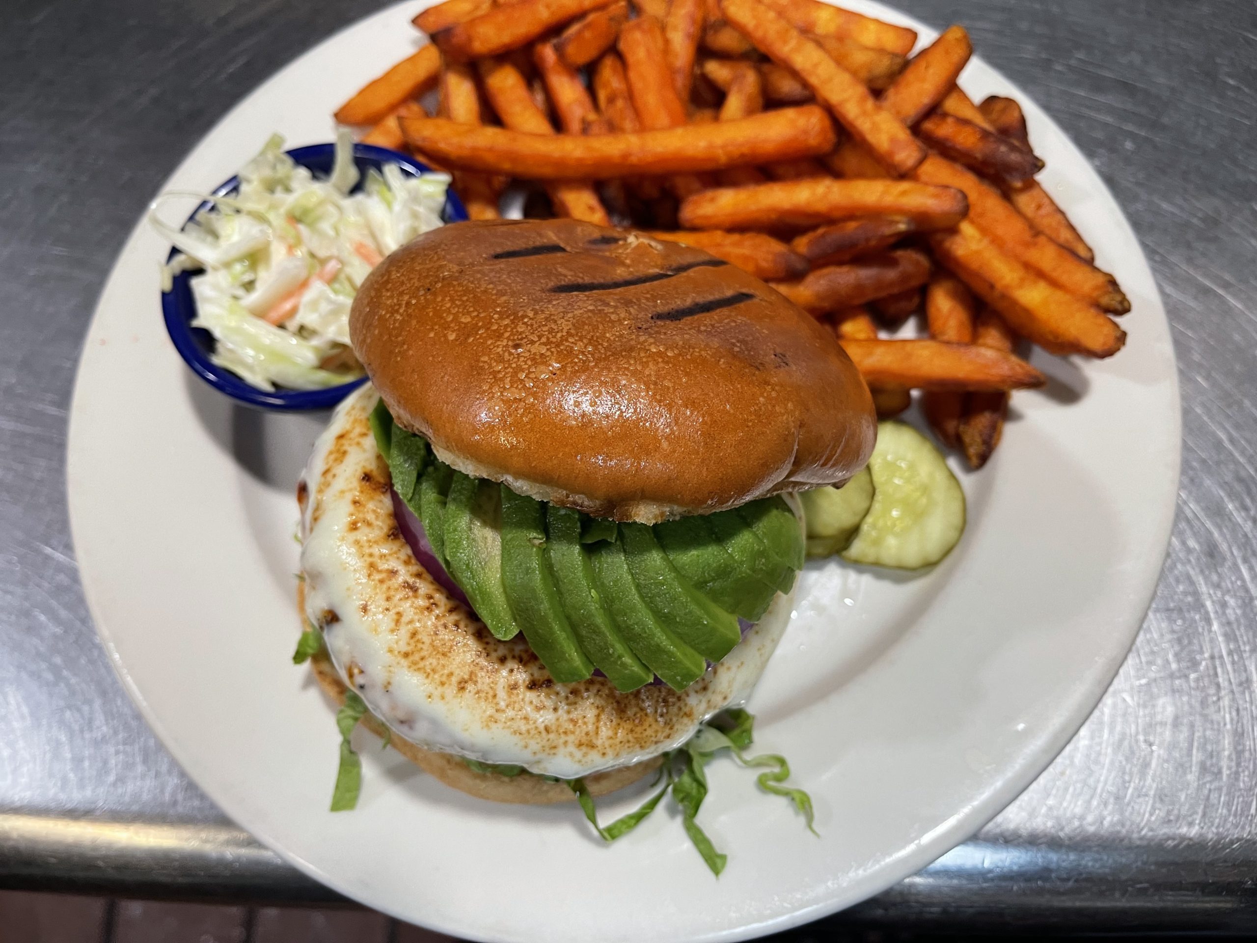 A burger with fries and avocado on a plate.