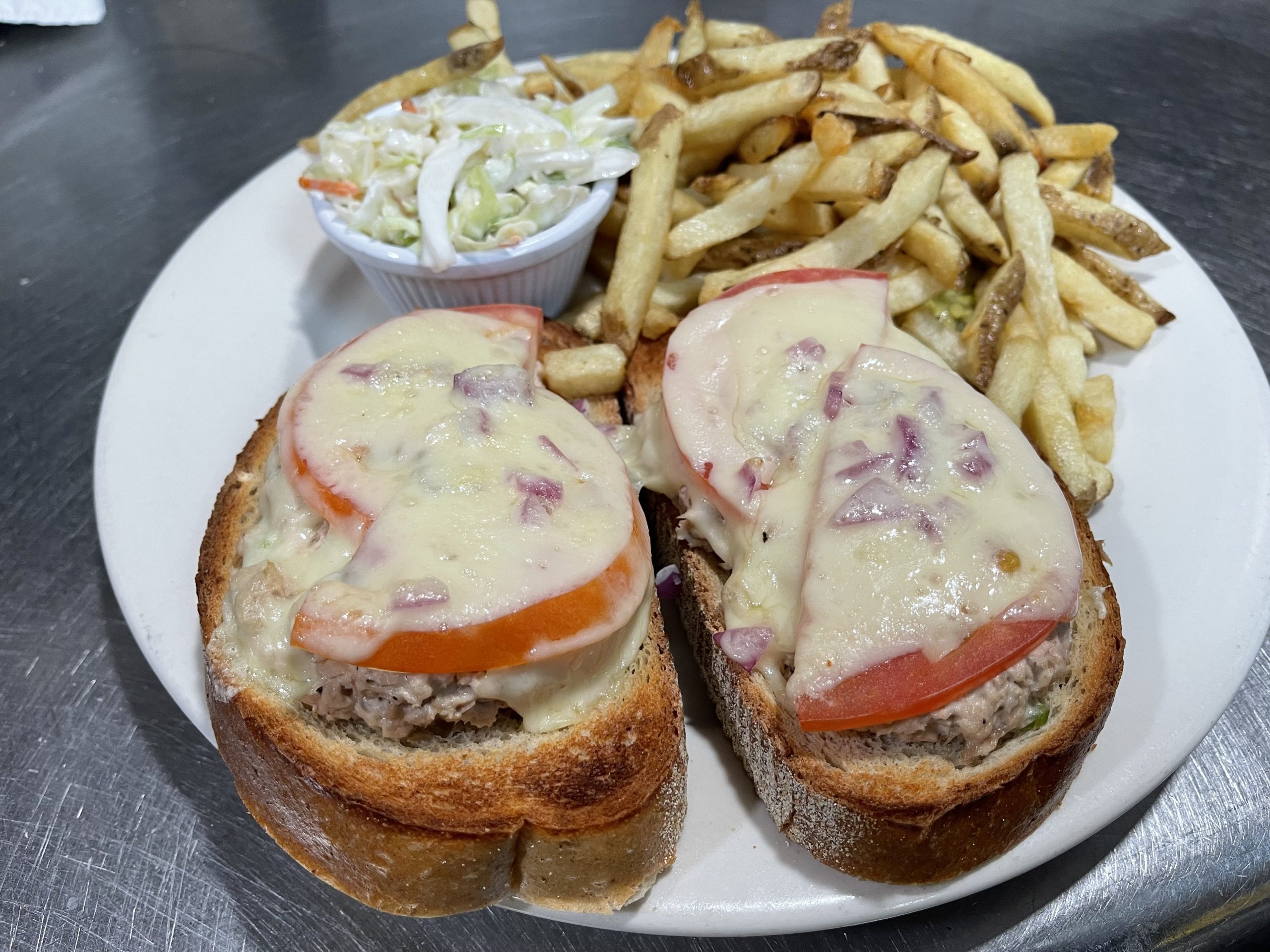 A sandwich with meat and tomato on a plate with french fries.