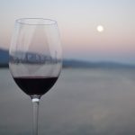 A glass of red wine with the moon in the background.