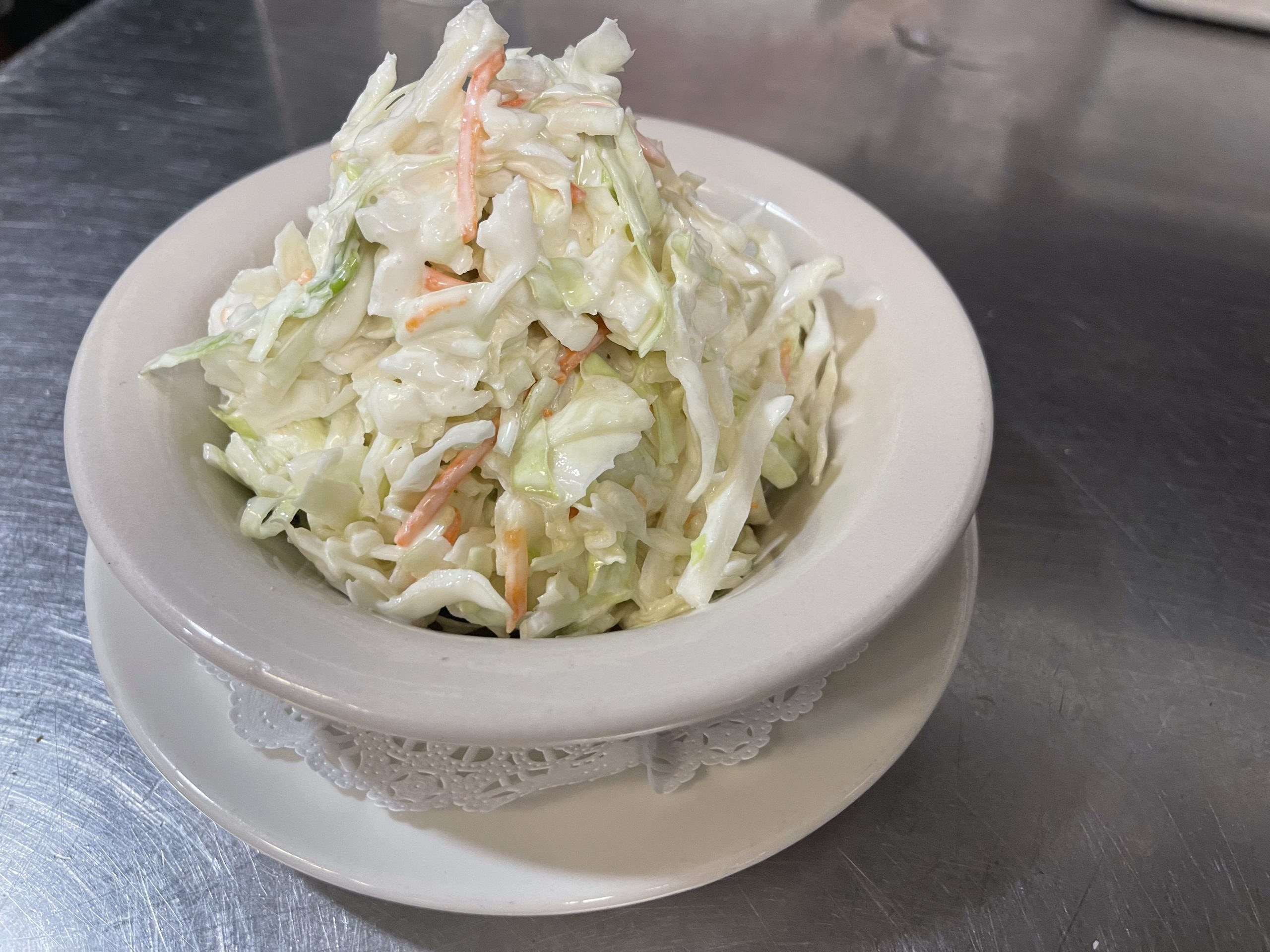 A bowl of coleslaw sitting on top of a plate.
